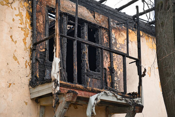 Facade of an old house after a fire. Burnt residential building balcony. Exterior of destroyed house.