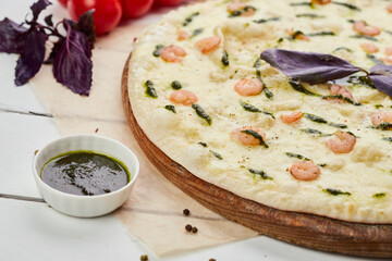 Freshly baked tasty pizza with shrimps and mozzarella cheese served on wooden background with tomatoes, sauce and herbs. Food delivery concept. Restaurant menu