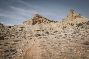 Curvy dirt trail through desert terrain in spring in central Utah near Goblin Valley underneath ...