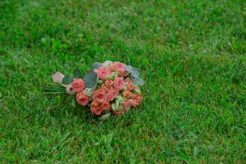 A beautiful wedding bouquet of natural flowers lies on the green grass wedding day