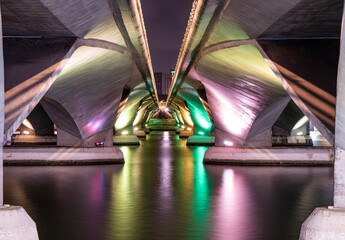 Colorful lights under the bridge with reflection on water surface