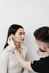 Otoplasty is surgical reshaping of the pinna, or outer ear for correcting an irregularity and improving appearance. Surgeon doctor examines girl ear before otoplasty cosmetic surgery.