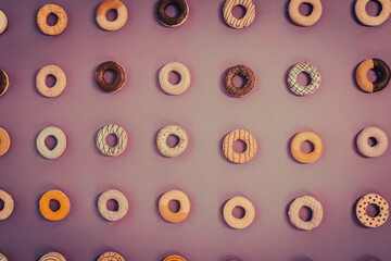 Round donuts food with different decoration on a solid purple pink background