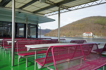 Tisch und Bank aus Drahtgeflecht auf dem grünen Schiffsdeck eines Ausflugsschiff bei Sonnenschein...