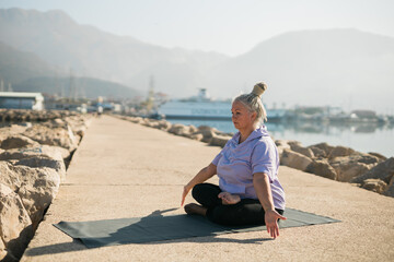 Fototapeta na wymiar Mature old woman with dreadlocks practicing yoga and tai chi outdoors by the sea - wellbeing and wellness