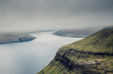 Aerial moody view from the Sornfelli mountain in Faroe Islands to the Vagar and Streymoy island, Denmark, Northern Europe, rainy and cloudy weather