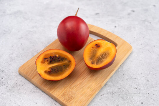 Fresh Exotic Fruit Tamarillo Sliced On Wooded Cutting Board On Table. Egg-shaped Edible Fruit Known As Tree Tomato, Plant Family Solanaceae, Solanum Betaceum. Top View. Flat Lay. Horizontal Plane