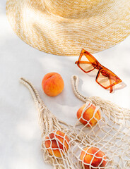Summertime fashion still life depicting beach accessories, fruits and a bottle of water. Stylish vacation stories with traveling theme and seashore tropical lifestyle. Safe tanning and sun screening.