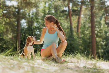 portrait of Caucasian woman and beagle dog in nature in park. cute pet having fun on vacation....