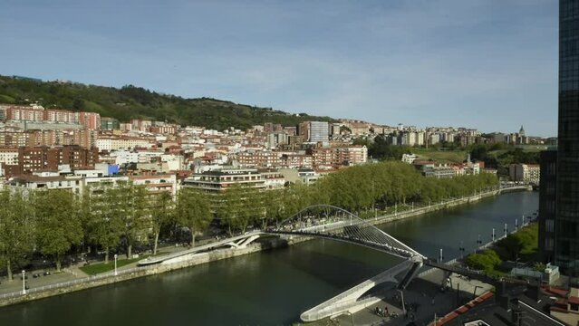 High perspective timelapse of Zubizuri arch footbridge crossing the Nervion River in Bilbao, Spain