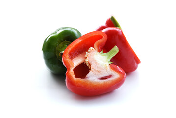Sweet bell peppers, just washed wet and shiny. Whole and halved fruit, red and green colors contrast on white background. Ripe fresh Bulgarian peppers. Tasty healthy food from Greek garden.
