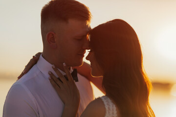 The bride hugs the groom on the sunset. Close-up. Wedding ceremony outdoors on the seashore.