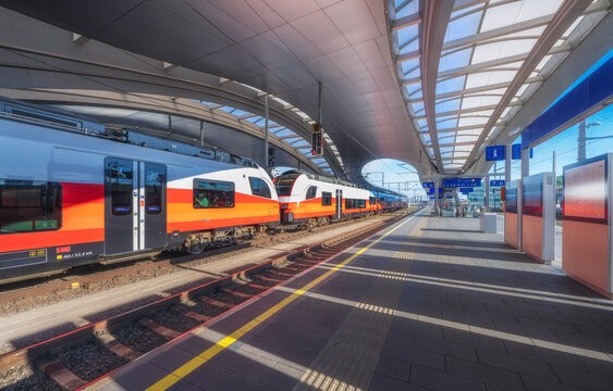 High speed train on the modern railway station at sunset in Graz, Austria. Beautiful orange intercity passenger train on the covered railway platform. Railroad. Passenger railway transportation