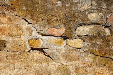 Close up view to old cracked yellow brick wall during the sunny day.