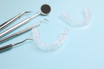 Transparent plastic aligners and dentist's tools on a colored background
