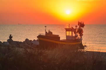 Colorful morning landscape by the sea. Beautiful boat on the beach with the rising sun. Photo taken...