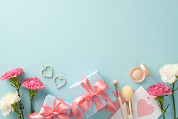 Mother's day concept. Top view flat lay photo of beautiful present boxes with pink ribbon, carnation flowers earrings makeup brushes on pastel blue background with empty space for text or advert