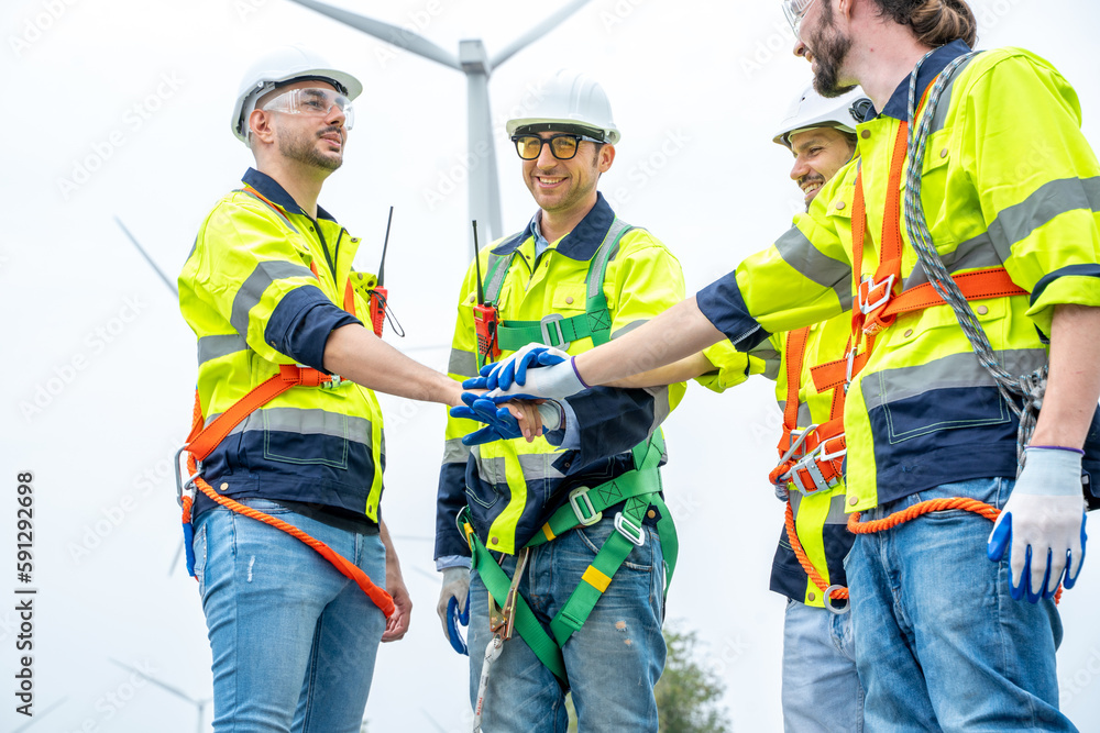 Poster engineers handshake after inspection work in wind turbine power generator station.