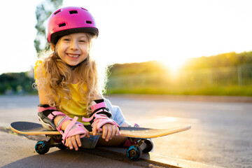 little beautiful girl with long blonde hair in a helmet with skate outside in summer, child smiling, space for text © Надежда Урюпина