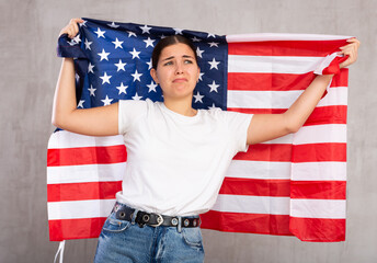 Frustrated girl with flag of United States of America flag in her hands. Isolated on gray background