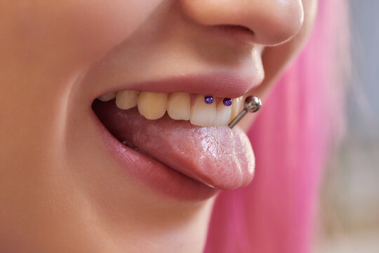 Girl lower lip piercing. Labret piercing. Macro. Blue ball.