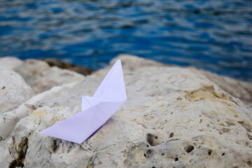 Paper boat on the rocks by the sea, travel concept