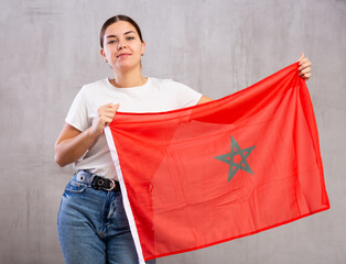 Young positive woman holding national flag of Morocco in her hands