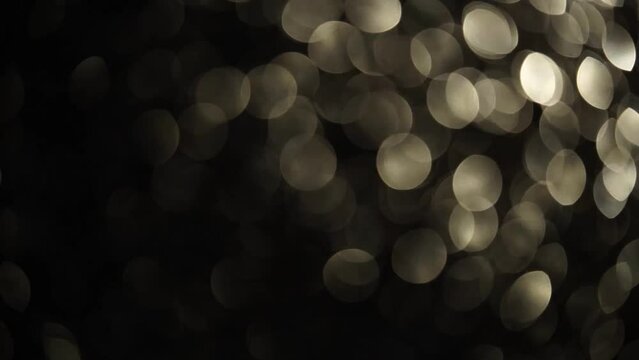 Slow diagonal movement of silver bokeh. The overflow motion of light defocused circles from corner to corner. Abstract moving silvery bokeh lights 4K background.