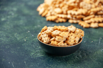 front view little salted crackers inside plate and on a dark background crisp color snack cips salt pepper bread dry rusk food