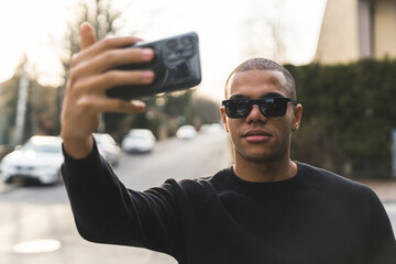 African American man in sunglasses taking selfie of himself outside in the street. High quality...