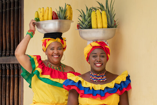 Cheerful fresh fruit street vendors aka Palenqueras in the Old Town of Cartagena de Indias, Colombia. Happy Afro-Colombian women in traditional clothing, Colombian culture and lifestyle.	
