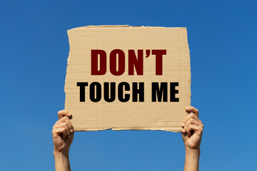 Don't touch me text on box paper held by 2 hands with isolated blue sky background. This message...