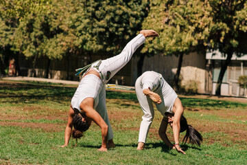 mujeres practicando patadas, ejercicios y capoeira en la ciudad con su ropa de capoeira en un...