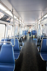 An adult woman in jeans rides in an empty subway car.