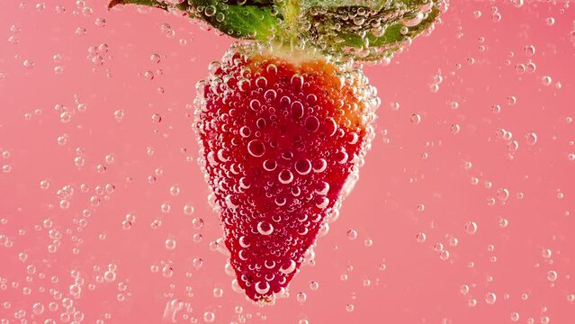 Ripe strawberries in air bubbles on a pink background.