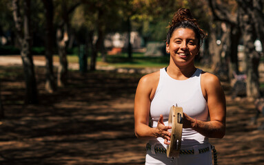 bella mujer morena sonriente brasilera con ropa de capoeira posando en un parque en un día soleado
