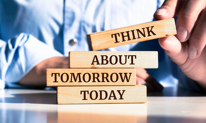 Close up on businessman holding a wooden block with "Think about tomorrow today" message