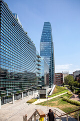 Obraz premium A modern building's green roof and glass facade reflect the surrounding cityscape.