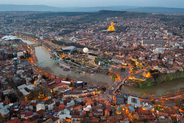 Obraz premium Picturesque general view from drone of Georgian city of Tbilisi on banks of Mtkvari River at spring dusk