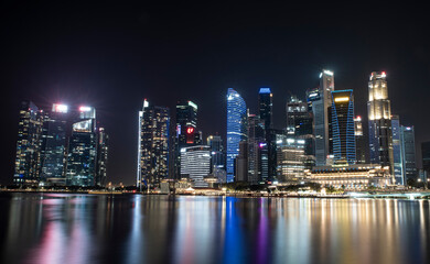 Singapore business district skyscrapers at night with reflection in water