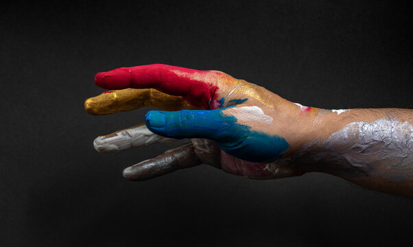 Artist's hand, in vivid colors on a dark background. An explosion of color and creativity