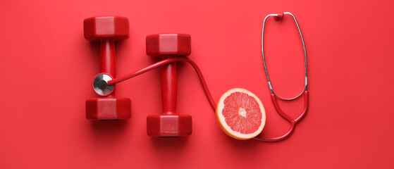 Stethoscope, grapefruit and dumbbells on red background. Weight loss concept