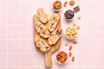 Composition with wooden board with tasty biscotti cookies, nuts and chocolate on color tile background