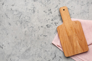Wooden cutting board with napkin on grunge background