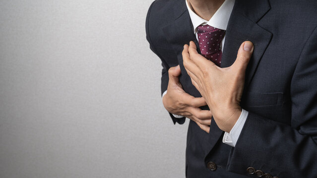 胸の痛み襲われるビジネスマン｜心筋梗塞・動悸・胸焼けなどのイメージ