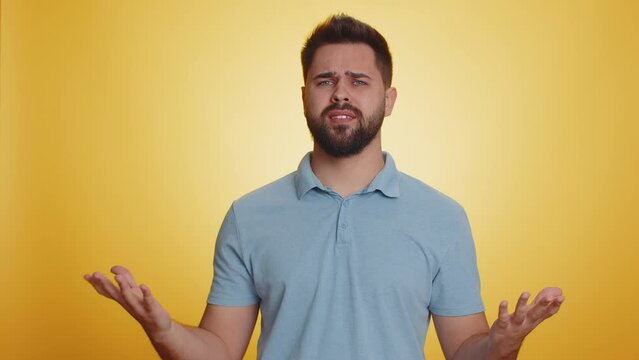 What Why. Sincere irritated caucasian man raising hands in indignant expression asking reason of failure demonstrating disbelief irritation by trouble. Handsome confused guy on yellow background