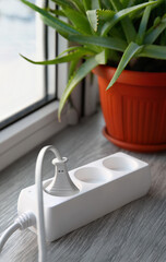 Electric extension cord with plugs on wooden windowsill