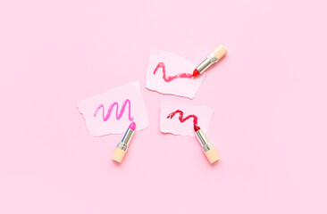 Lipsticks and papers with strokes on pink background