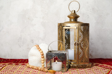 Muslim lamps with prayer beads and hat on mat near wall