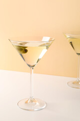 Glasses of martini with olives on beige background